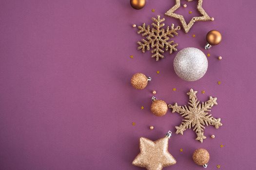 Christmas Border frame of golden glitter ornaments on purple paper background with copy space for text