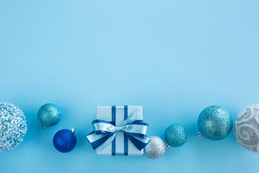 Blue Christmas holiday gift and decor frame on blue background, small decorated box with ribbon bow