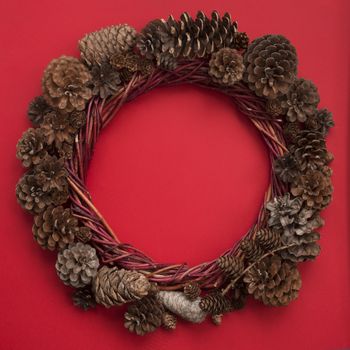 Christmas natural eco style spruce pine cone wreath over red background flat lay top view with copy space for text