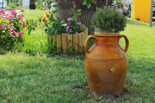 old brown clay pot placed in a flowerbed