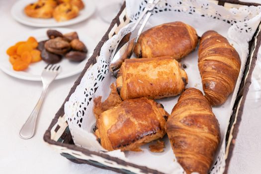 Breakfast with dried fruits and croissants in a basket on table