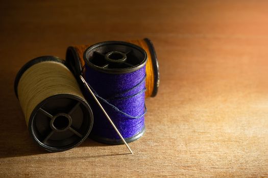 Needle and threads on wooden table. Closeup and copy space for text. Concept of tailor or Designer.