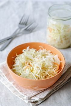 Orange bowl with crunchy sauerkraut served on napkin with forks on table