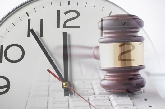 Double exposure of wooden and brass gavel on computer keyboard and clock on white background