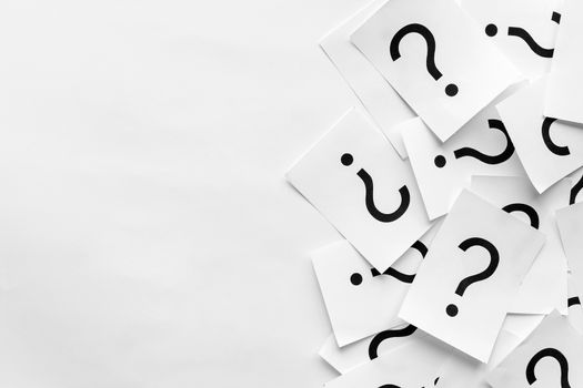 Pile of question marks printed on white cards forming a side border over a white background with copy space in a conceptual image