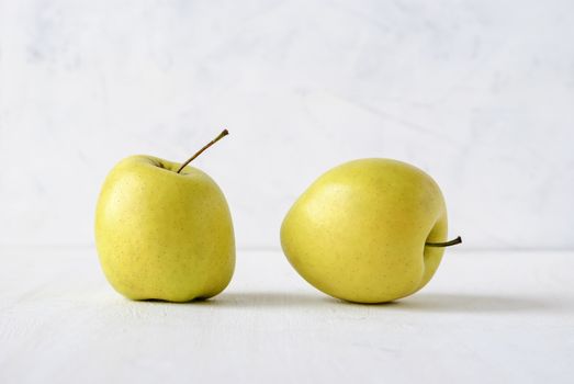 Two ugly misshapen golden fresh apples viewed side by side low angle on white