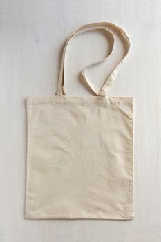Natural fiber neutral coloured re-usable shopping bag with handles laid flat on a white background