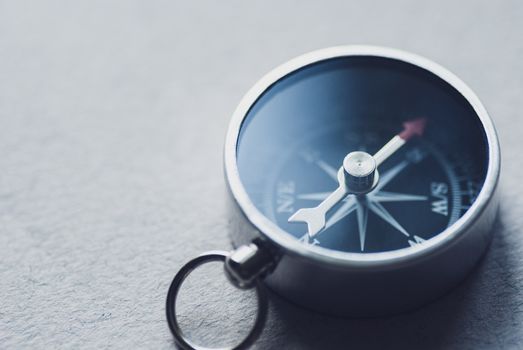 Small magnetic compass for navigation on a grey background with coy space in a conceptual image