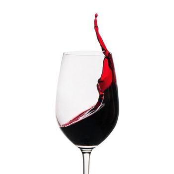 Freeze motion of red wine splashing up the side in a wineglass isolated on white with copy space