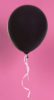 Black balloon isolated on a pink background