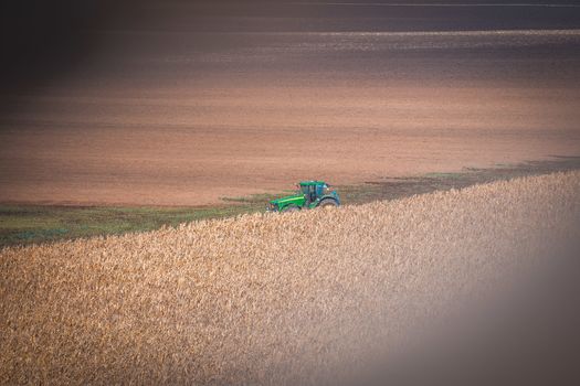 Large tractor pulling plow, throwing dust up in the air.