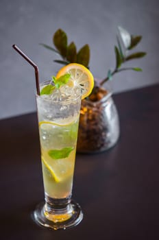 Mojito cocktail with lime and mint in high glass on wooden table.