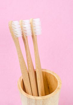 Bamboo toothbrushes on pink background. Zero waste concept.