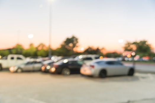 Abstract blurred parking lot of modern shopping center in Houston, Texas, USA. Exterior view mall complex with row of cars in outdoor uncovered parking, bokeh light poles in background