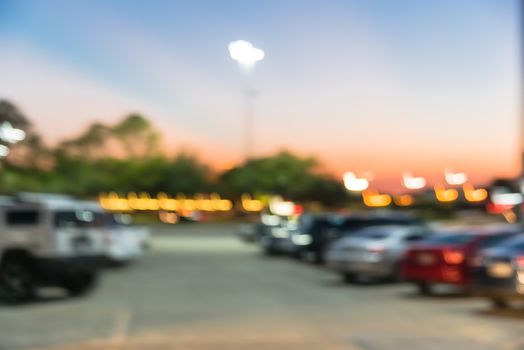 Abstract blurred parking lot of modern shopping center in Houston, Texas, USA. Exterior view mall complex with row of cars in outdoor uncovered parking, bokeh light poles in background