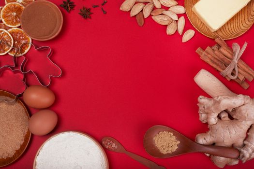 Christmas gingerbread cookies cooking background flat lay top view template with copy space for text. Baking utensils, spices and food ingredients on red paper