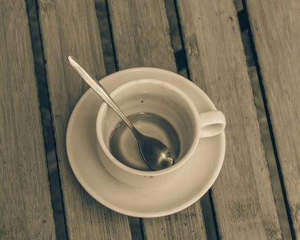 Empty cup of traditional Vietnamese milk coffee on outdoor wooden table. Popular white ceramic cup and saucer.