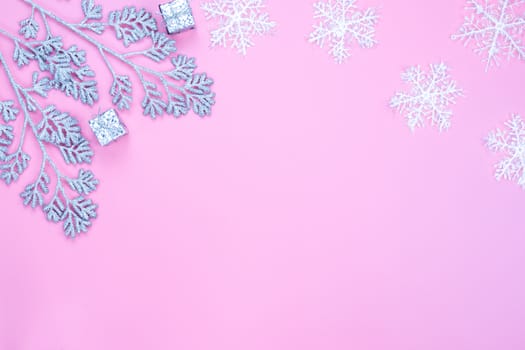 Christmas holidays composition, top view of silver Christmas decorations and snowflakes on pink background with copy space for text. Flat lay, winter, postcard template, new year concept.