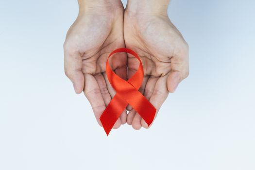 Aids awareness, male hands holding red AIDS awareness ribbon on white background. World Aids Day, Healthcare and medical concept.