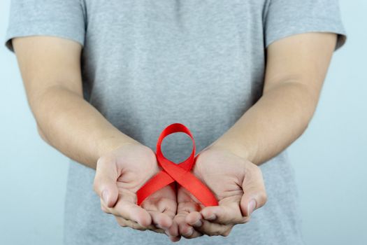 Aids awareness, male hands holding red AIDS awareness ribbon. World Aids Day, Healthcare and medical concept.