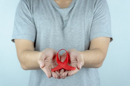 Aids awareness, male hands holding red AIDS awareness ribbon. World Aids Day, Healthcare and medical concept.