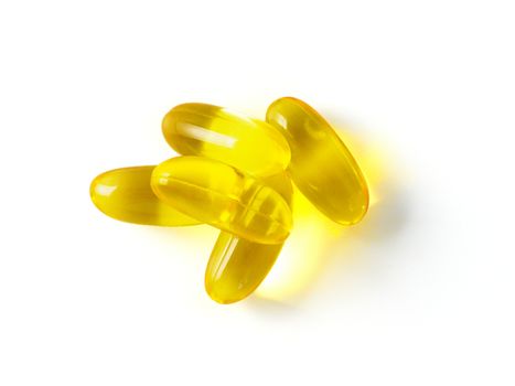 Omega 3 fish oil capsules isolated on white background. Golden color capsules - vitamin E, D or multivitamin.