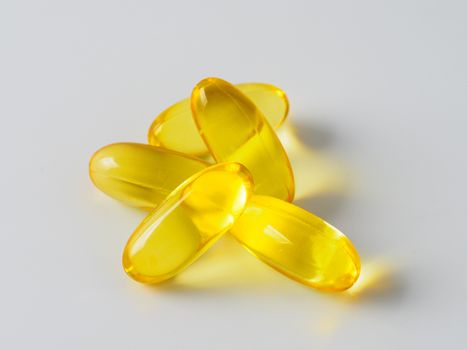 Omega 3 fish oil capsules isolated on white background. Golden color capsules - vitamin E, D or multivitamin.