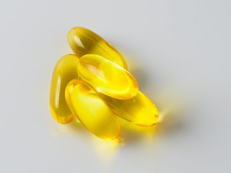 Omega 3 fish oil capsules isolated on white background. Golden color capsules - vitamin E, D or multivitamin.