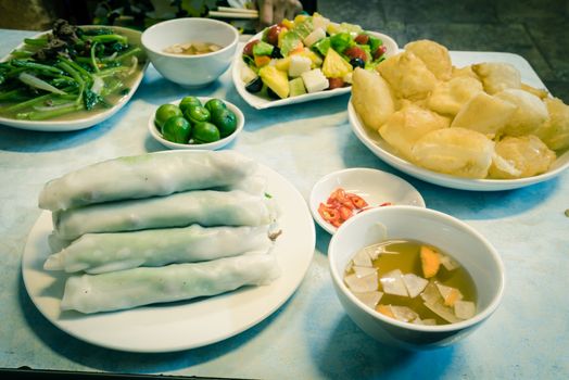 Lunch food arrangement of rice noodle roll (Pho cuon) and inflated fried rice noodles or rice noodle pillows (Pho chien phong) in Hanoi, Vietnam. Fish sauce, garlic, carrot, vinegar, chili, salad