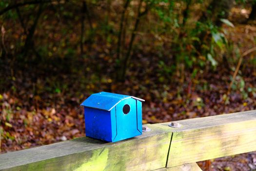 An old wooden Blue Birdhouse on Wood Railing in the forest