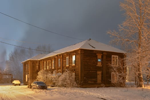 Winter street in night illumination with an old house in the foreground
