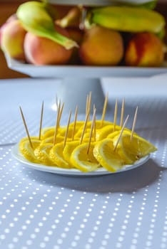 Yellow lemon slice standing on a white plat on blurred table