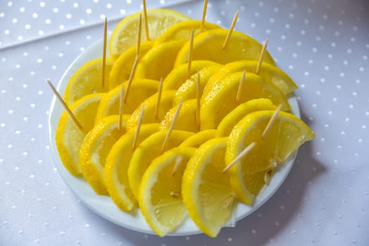 Yellow lemon slice standing on a white plat on blurred table