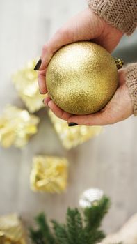 Hand holding gold ball decorations on Christmas tree background. for Christmas and Happy New Year