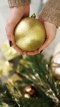 Hand holding gold ball decorations on Christmas tree background. for Christmas and Happy New Year