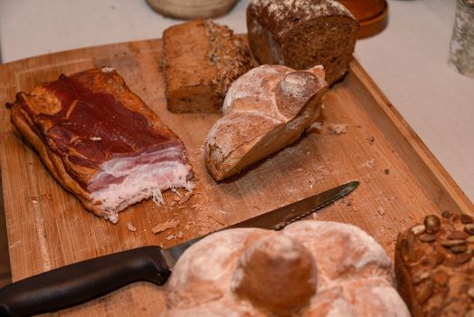 Smoked bacon with bread and knife on cutting board