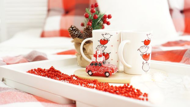 New Year or Christmas red mug on white tray in red and white bed with lights