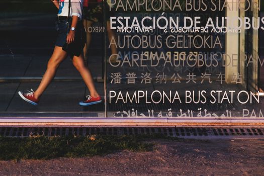 Pamplona bus station signal in various languages with a person walking at the background