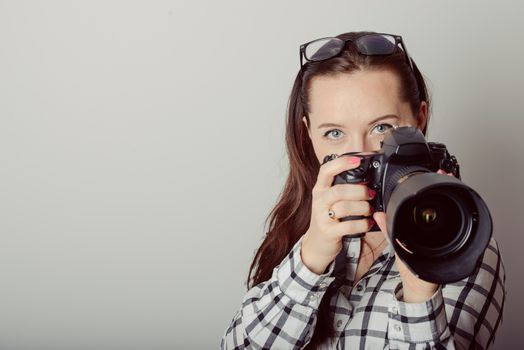 Woman-photographer takes images, isolated on gray background