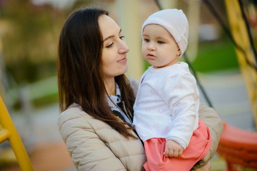 Happy mother and daughter in the park. Beauty nature scene with family outdoor lifestyle. Happy family resting together on the green grass, having fun outdoor. Happiness and harmony in family life.