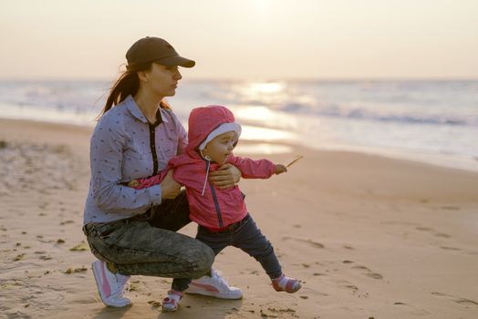 Mother and little daughter playing on the beach. Authentic image.