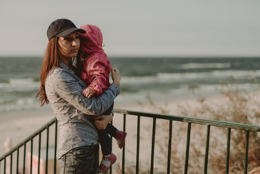 Mother and little daughter playing on the beach. Authentic image.