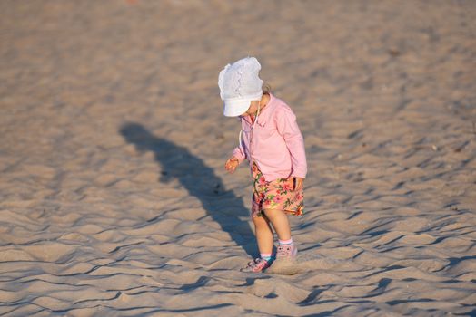 Adorable toddler girl on a sunny sand beach. Authentic childhood
