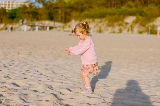 Adorable toddler girl on a sunny sand beach. Authentic childhood