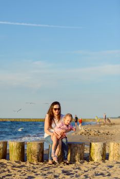 Mother and little daughter playing on the beach. Authentic image.