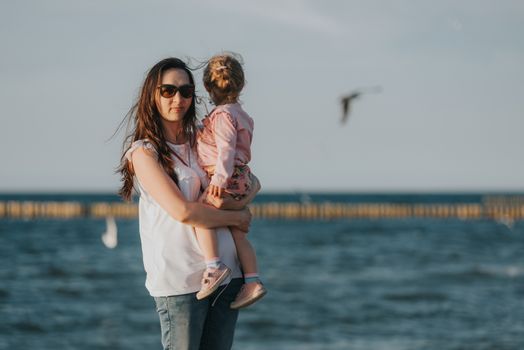 Mother and little daughter playing on the beach. Authentic image.