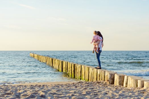 Mother and little daughter playing on the beach. Authentic image.