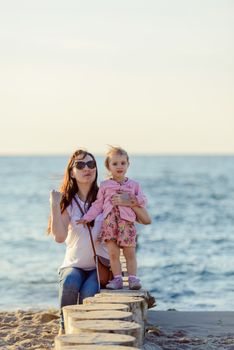 Mother and little daughter playing on the beach. Authentic image.