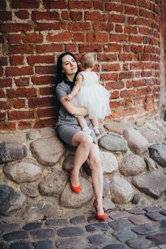 Happy mother and daughter in the park. Beauty nature scene with family outdoor lifestyle. Happy family resting together on the green grass, having fun outdoor. Happiness and harmony in family life.