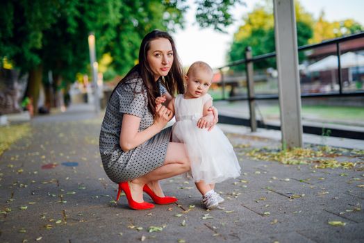 Happy mother and daughter in the park. Beauty nature scene with family outdoor lifestyle. Happy family resting together on the green grass, having fun outdoor. Happiness and harmony in family life.